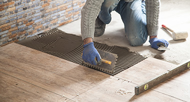 a person laying cement while laying down vinyl flooring