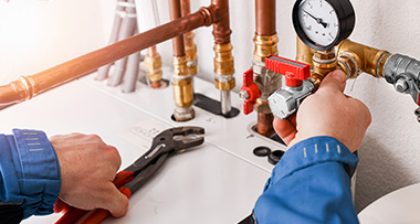 a person using a spanner to fix a plumbing system