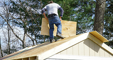 a man on a shed roof installing the roof panels