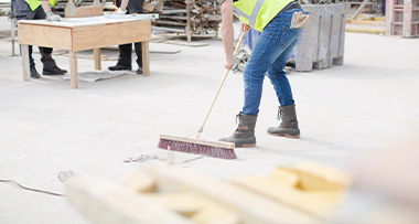 a person sweeping debris on a construction site to keep the clear