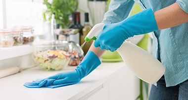 a person wearing rubber gloves cleaning a surface in a kitchen