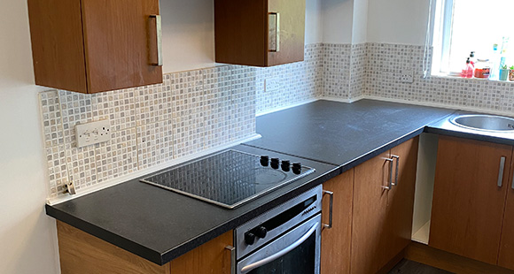 a refurbished kitchen with dark brown cabinets and black countertops