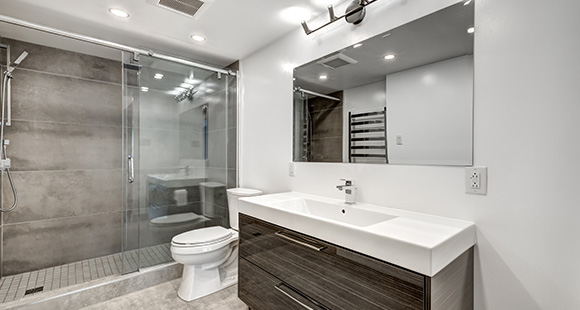 a bathroom newly renovated with a wet section for the shower, and glossy wooden cabinets 