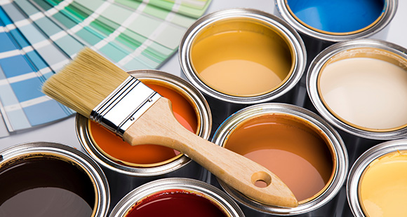 a number of different buckets of coloured paints, with a brush sitting on top and a Pantone swatch behind