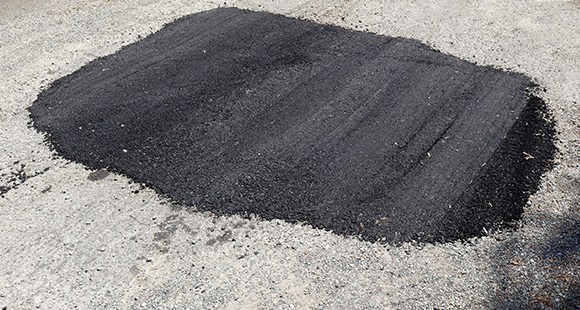 a large patch on a road repaired with tarmac 