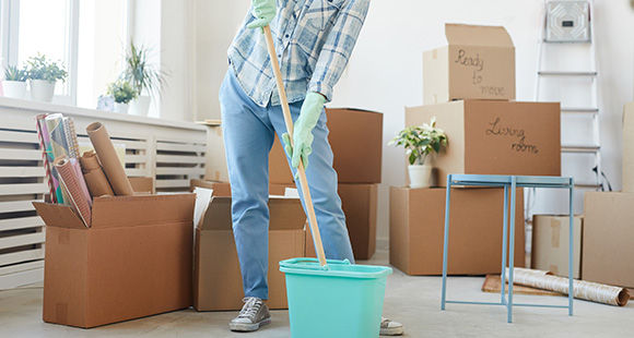 a person using a mop to clean the floor of a flat of tenants moving out 