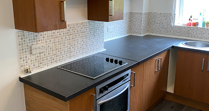 a newly refurbished kitchen with dark brown cupboards and black countertops