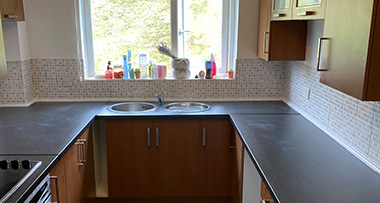 a renovated kitchen with black countertops and wooden cabinets