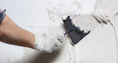 a person using a trowel to apply plaster to a wall